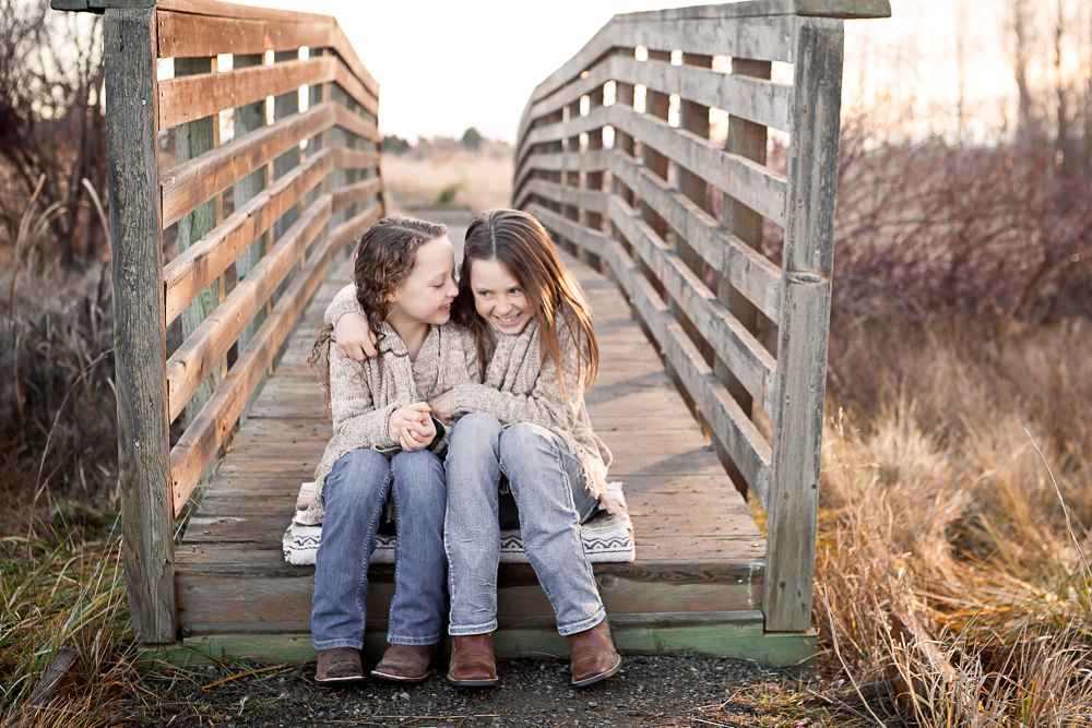 sisters whispering on rustic bridge - ellensburg children photographer
