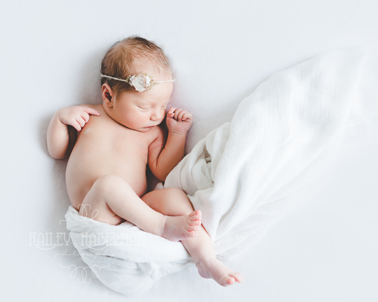 Nora Newborn session photo of baby asleep on back with handmade headband in natural pose