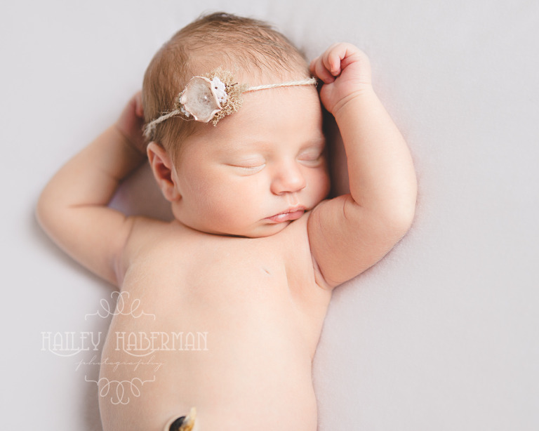 Nora Newborn session photo of baby asleep on back with hand above her head